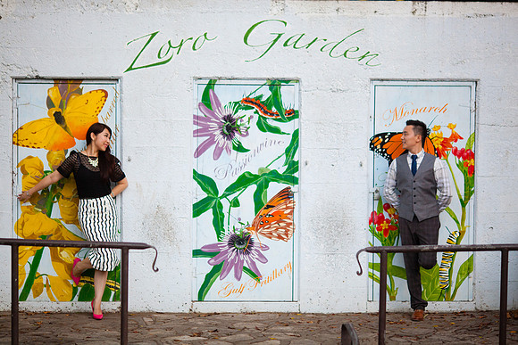 Cute, fashionable couple stands agains a brightly colored wall mural featuring flowers, butterflies, and the words "Zoro Garden" at a location near Balboa Park in San Diego, California