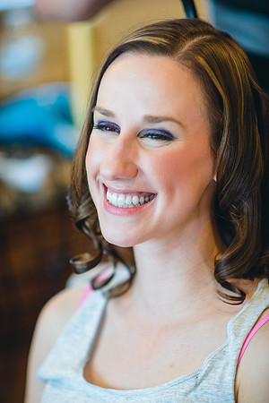 Smiling bride getting her bridal makeup and hair done