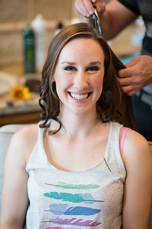 Smiling bride getting her hair and makeup done
